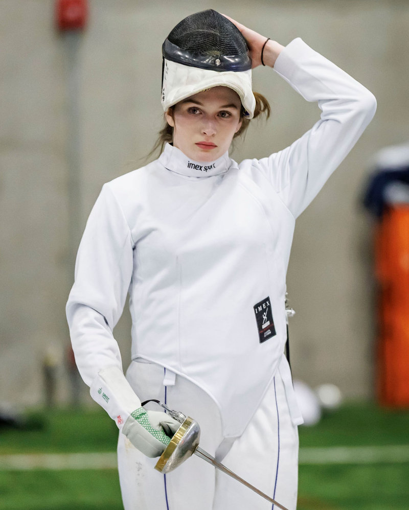Adult fencer adjusting her mask